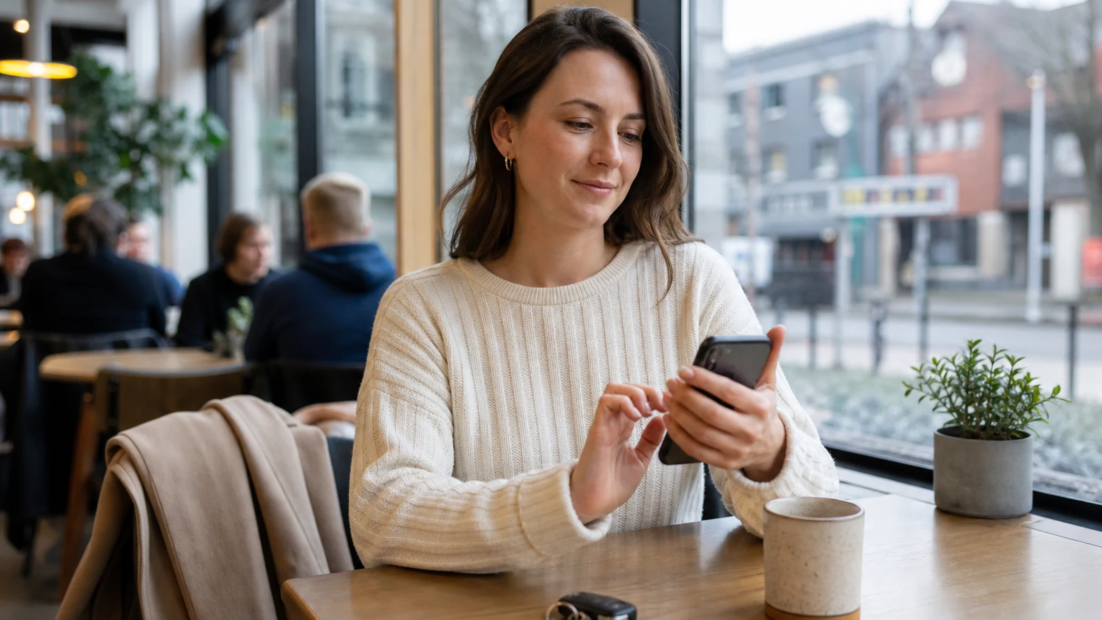 Woman reviewing phone privacy settings in a busy public Portland cafe